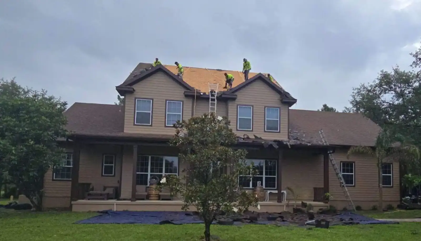 Roofing crew in safety gear replacing the roof of a two-story Florida home