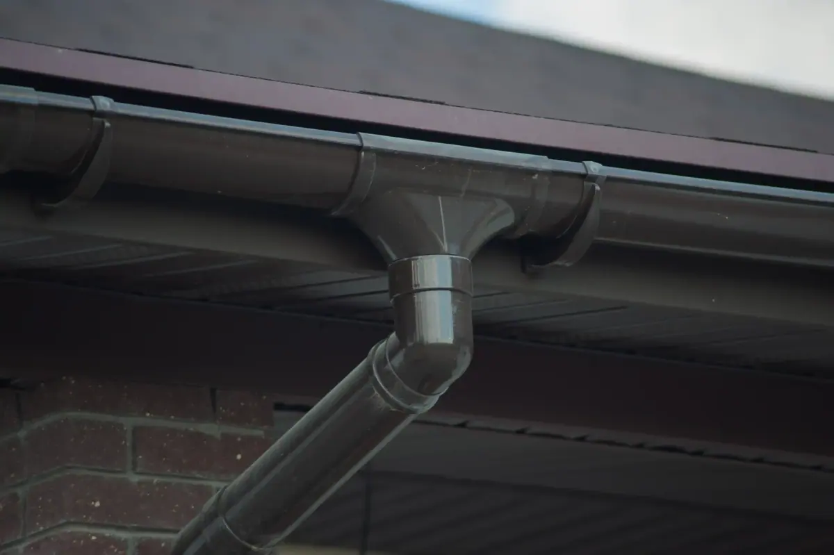 Corner of a house with a new gray metal roof and a metal rain gutter