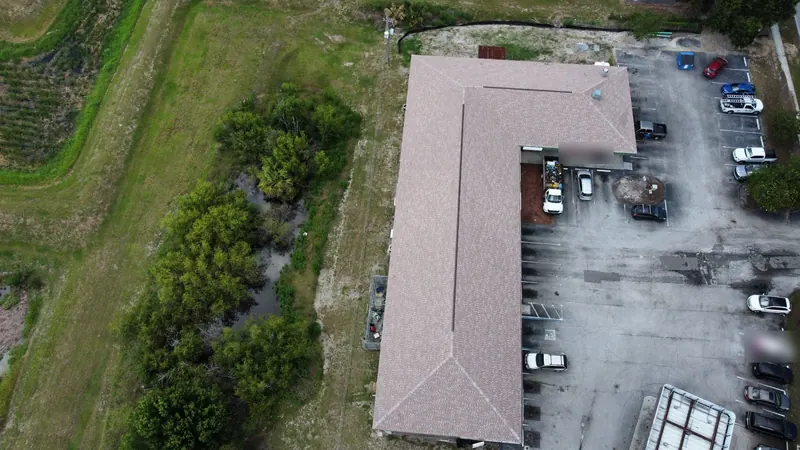 Drone view of an L-shaped commercial building in Lakeland with an asphalt shingle roof and a long ridge vent