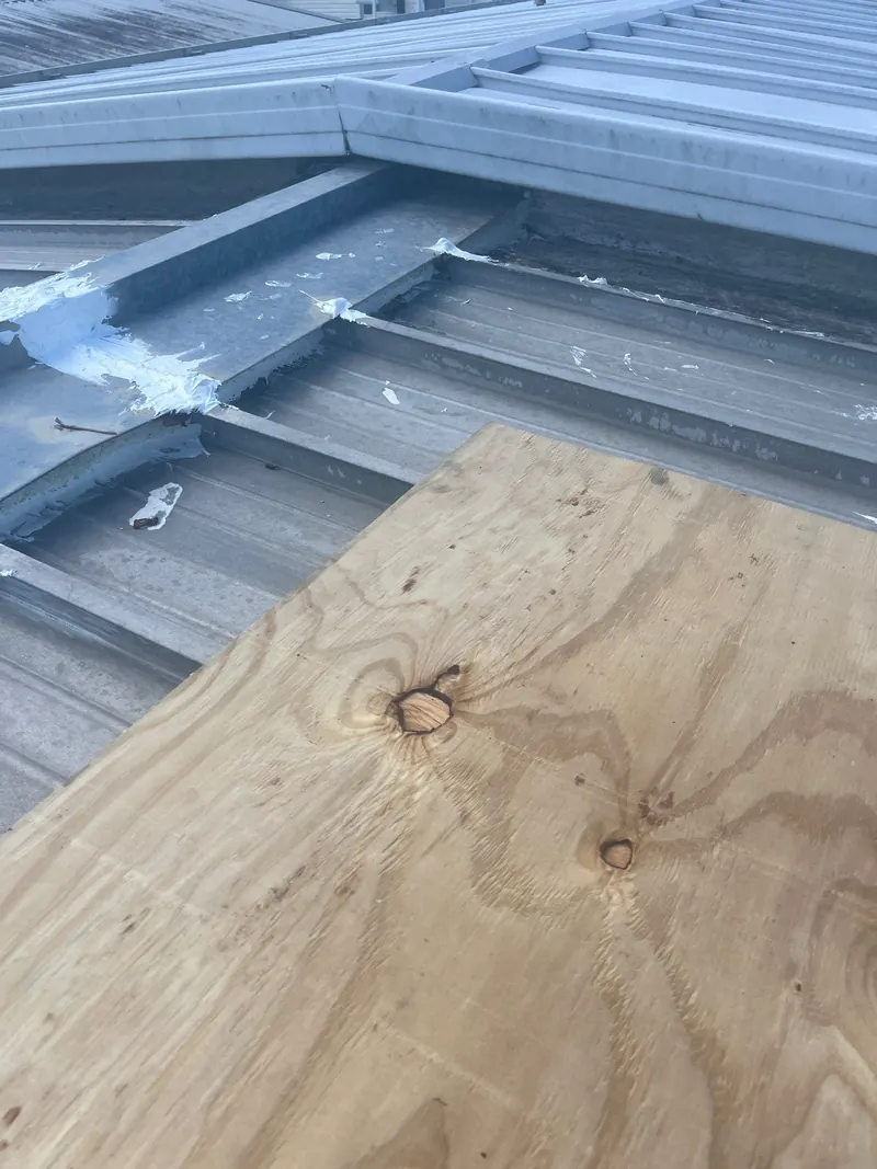 New plywood decking laid over the ribs of a metal roof during a repair